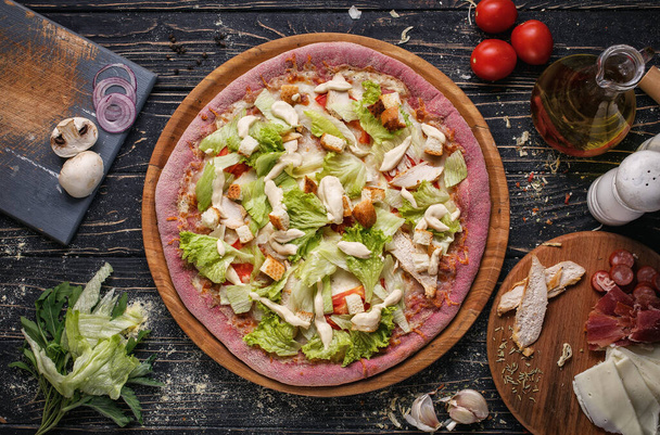 Вид зверху на піцу з курячим м'ясом, помідорами, хлібом і салатом на дерев'яних тарілках
. - Фото, зображення