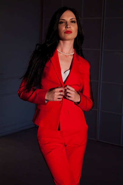 Ritratto di una donna d'affari bruna in abito da lavoro rosso in ufficio
 - Foto, immagini