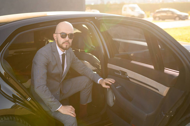a bald business man with beard in an expensive suit in an expensive car - Фото, зображення