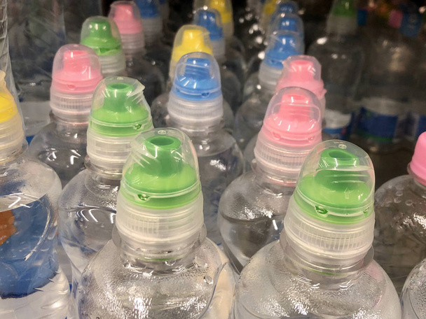Много бутылок газированной воды. Фон текстуры: пластиковые бутылки с лимонадом. Бутылки с минеральной водой имеют яркие колпачки
. - Фото, изображение