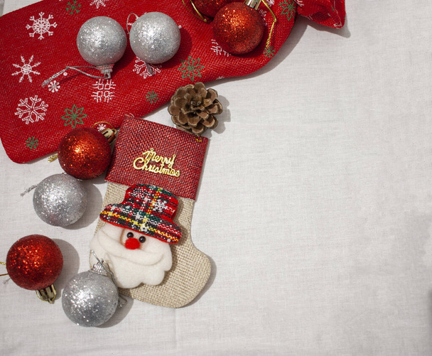 Ano Novo ou fundo de Natal com um saco de presente vermelho decorado com flocos de neve coloridos e brinquedos de Natal em um pano branco. Flat lay, espaço
. - Foto, Imagem