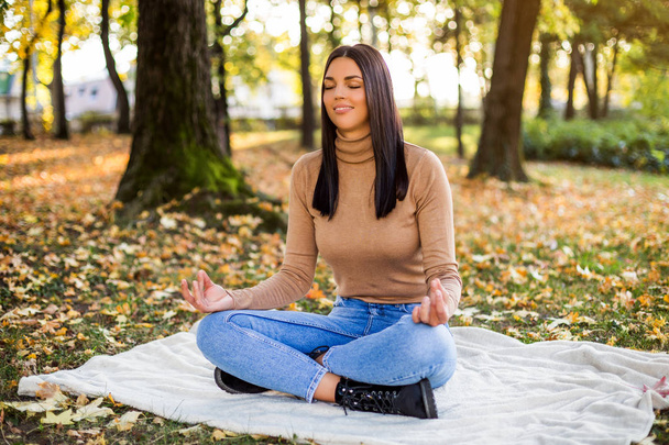 Beautiful woman meditating while resting and enjoys in autumn in the park. - Foto, afbeelding