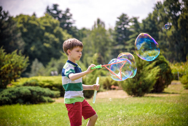 公園で石鹸の泡で遊んでいる小さな男の子。子アクティビティ。スプリングタイムコンセプト - 写真・画像