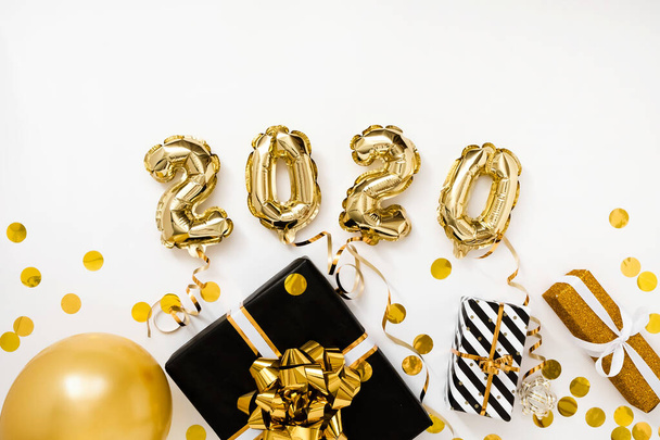 Happy New year 2020 celebration. Gold foil balloons numeral 2020 on white background with gifts - Photo, image