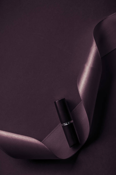 Luxusní rtěnka a hedvábná stuha na tmavě fialové dovolené backgroun - Fotografie, Obrázek