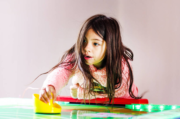 Geconcentreerd en enthousiast meisje speelt tafelhockey. - Foto, afbeelding