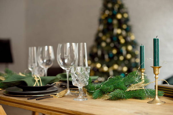 Christmas decoration with pine branches, table setting and candles on a dark Christmas tree background - Фото, зображення