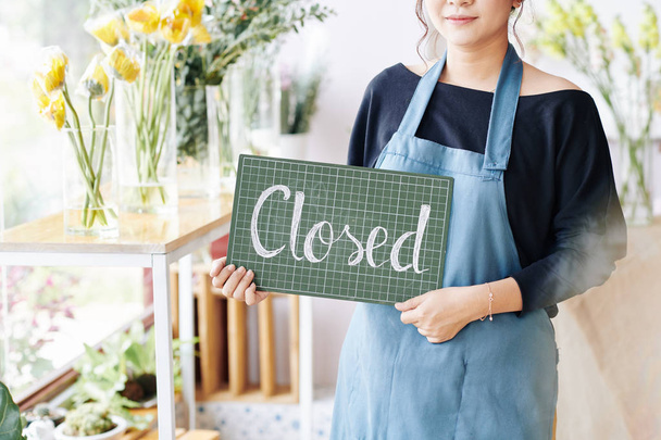 Vágott kép fiatal női bolt tulajdonosa gazdaság műanyag tábla zárt felirattal - Fotó, kép