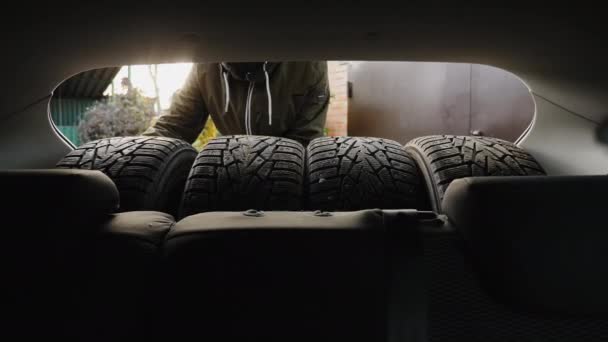 A man unloads winter tires from a car trunk - Footage, Video