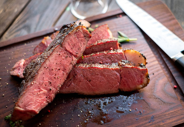 mittelseltenes Ribyey Steak in Stücke geschnitten an Bord - Foto, Bild
