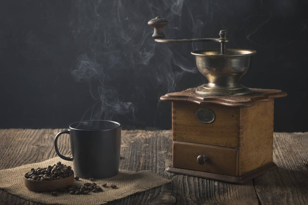 Antique coffee grinder with steaming coffee, and coffee beans - Fotoğraf, Görsel