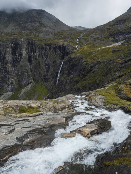 Plataforma de puntos de vista en Trollstigen o Trolls Sendero con valle verde y cascada en el macizo Trolltindene en el valle de Romsdal, Noruega. Nubes de cielo blanco nublado
. - Foto, imagen