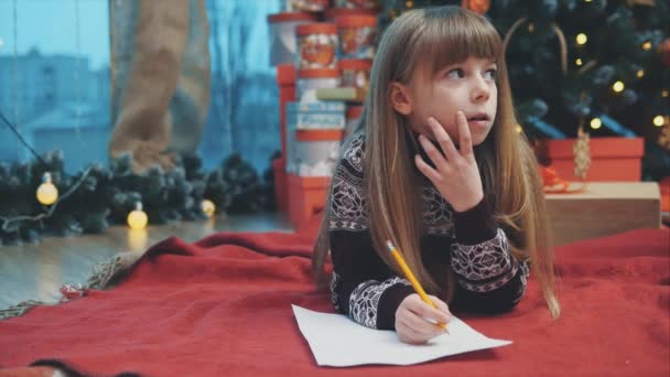 Happy child in knitted reindeer sweater, sealing envelope to Santa with Christmas presents wish list. - Záběry, video
