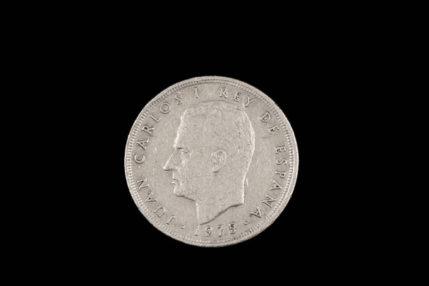 Una antigua moneda española de cinco pesetas con Rey Juan Carlos, rodado de cerca en macro, sobre un fondo negro
 - Foto, Imagen