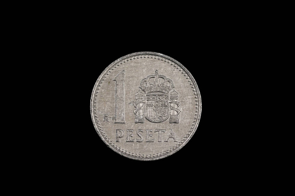 Una vieja moneda española de una peseta con Rey Juan Carlos, rodado de cerca en macro, sobre un fondo negro
 - Foto, Imagen