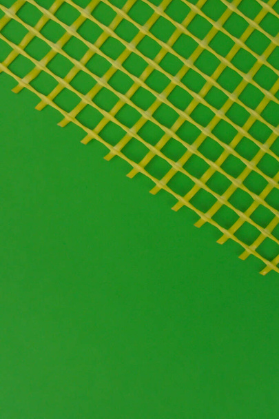 malla de plástico amarillo sobre papel verde claro
 - Foto, imagen