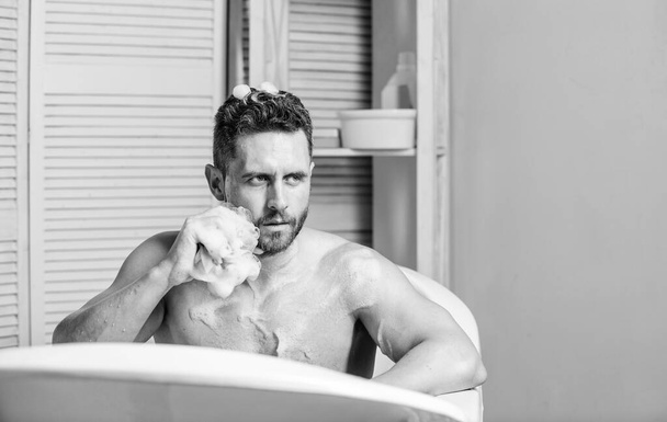 Man handsome muscular guy relaxing in bath. Spa wellness concept. Taking bath with soap suds. Treating yourself with hot or warm bath can feel like height of luxury. Pampering and beauty routine - 写真・画像