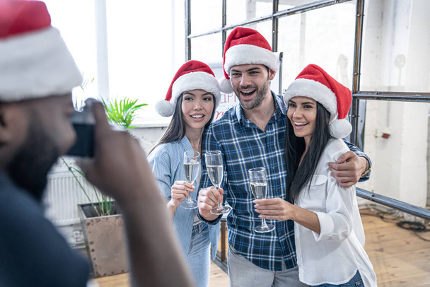Merry Christmas and Happy New Year 2020.Young creative people are celebrating holiday in modern office.Office workers posing for a photographer at a corporate event. Successful freelancers team - Foto, Imagen