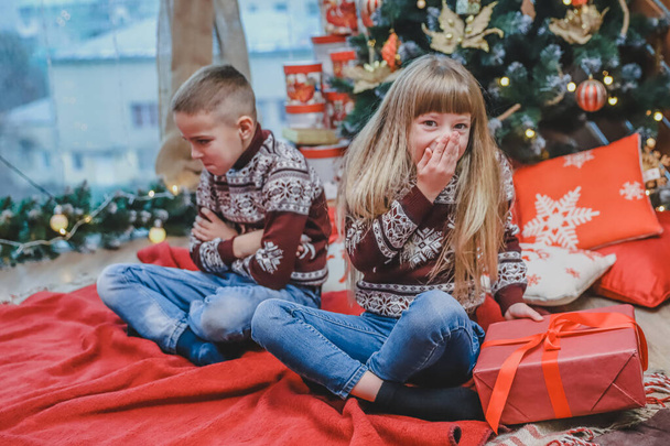 Greedy sister has stolen brothers present and looks at the camera with cunning face expression, while ffended boy is sitting near her looking upset. - Fotoğraf, Görsel