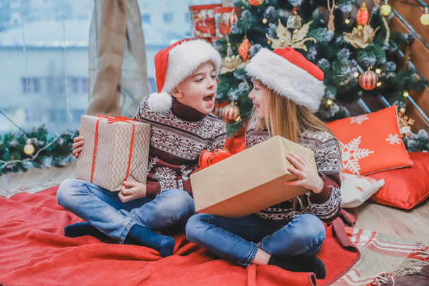 Santa-dressed children are teasing one another, competing whose present is better. - Zdjęcie, obraz