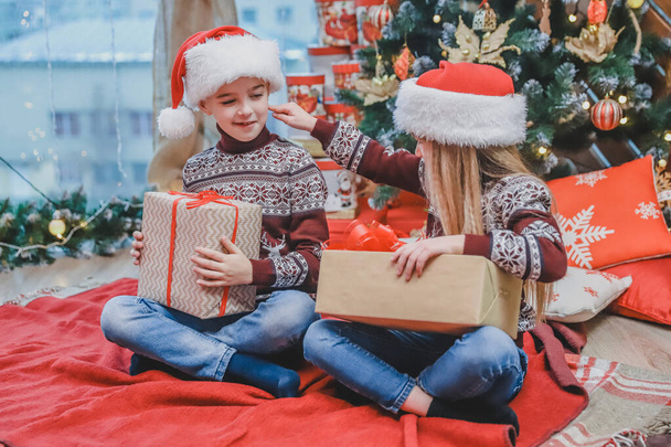 Santa-dressed children are teasing one another, competing whose present is better. - Zdjęcie, obraz