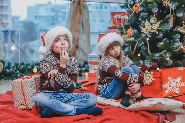 Photo of minded children on Christmas Eve, wondering about what they will get as a present. - Foto, Imagem