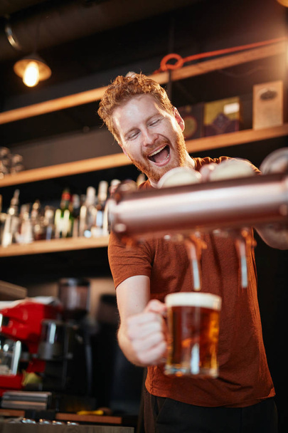 Красивий білий бармен поливає пиво, стоячи в пабі. Вибірковий фокус на людині
. - Фото, зображення