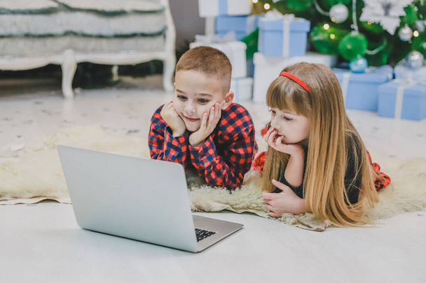 Amazing siblings buying christmas presents online with laptop together. - Valokuva, kuva
