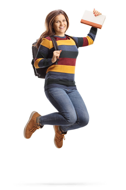 Female student jumping and holding a book - 写真・画像