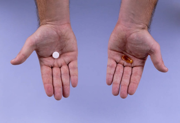 Les mains de l'homme donnent deux grosses pilules. Blanc et orange. Faites votre sele
 - Photo, image
