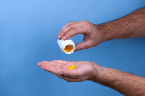 Man hand holds yellow medication capsules of omega 3, pours from - Photo, Image