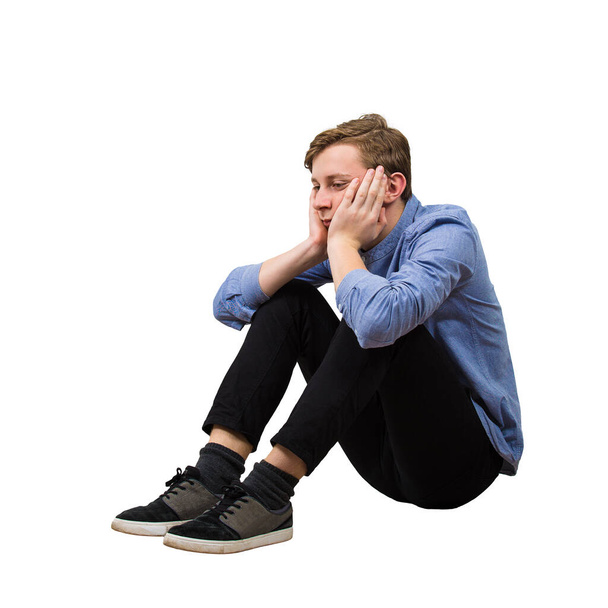 Вид сбоку в полный рост расстроенного и усталого мальчика-подростка, сидящего
 - Фото, изображение