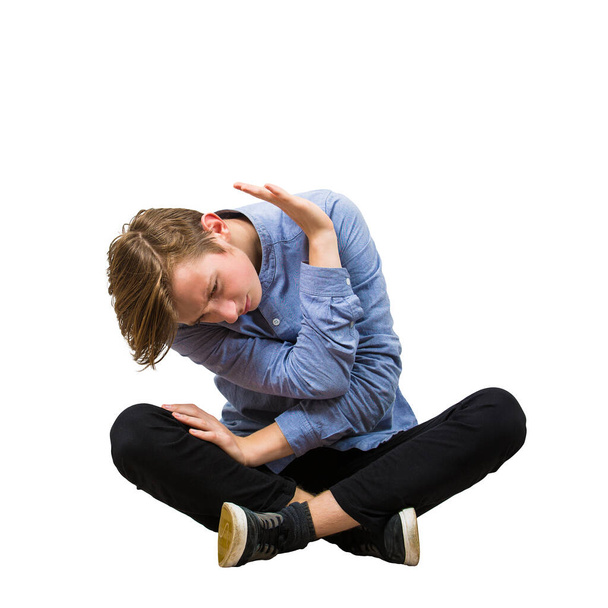 Испуганный подросток, сидящий на полу держит руку над головой
  - Фото, изображение