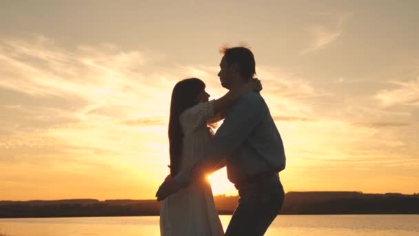 Amare l'uomo e la donna danzano in raggi di sole sullo sfondo del lago. coppia che balla al tramonto sulla spiaggia. Felice ragazzo e ragazza valzer la sera nel parco estivo
. - Filmati, video