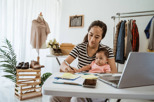 woman with baby working from home of her online ecommerce shop - Foto, immagini