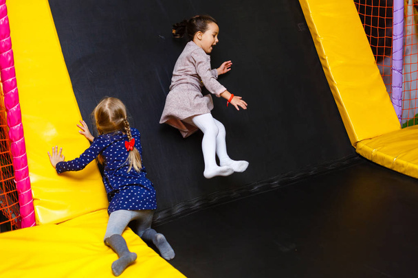 Παιδί άλμα σε πολύχρωμο τραμπολίνο παιδική χαρά. Δραστηριότητα και κέντρο παιχνιδιού για παιδιά  - Φωτογραφία, εικόνα