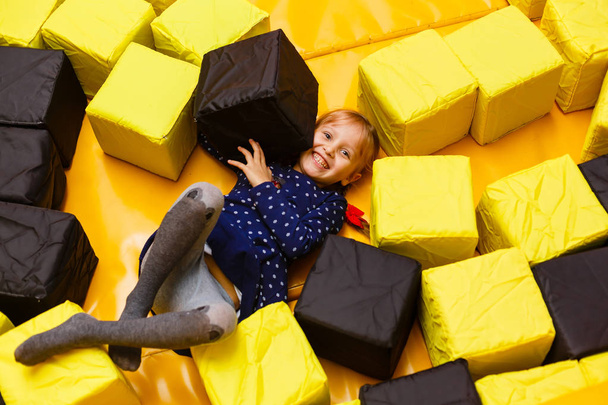 Щаслива смішна дівчина грає з іграшками, барвисті кулі на ігровому майданчику
 - Фото, зображення