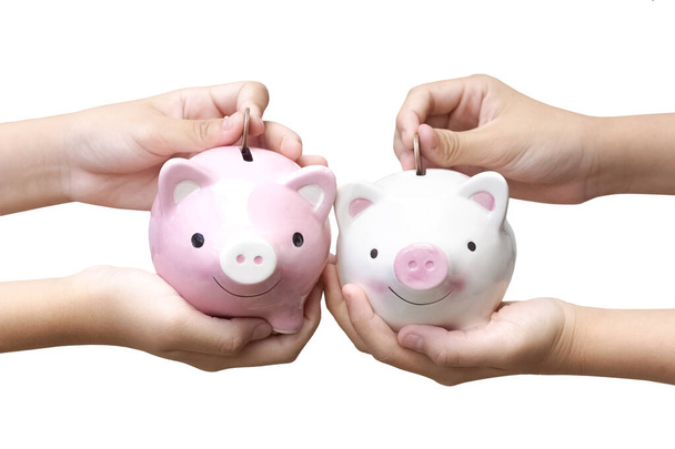 Saving money - Two kids holding and putting coins into piggy banks isolated on white background - Photo, Image