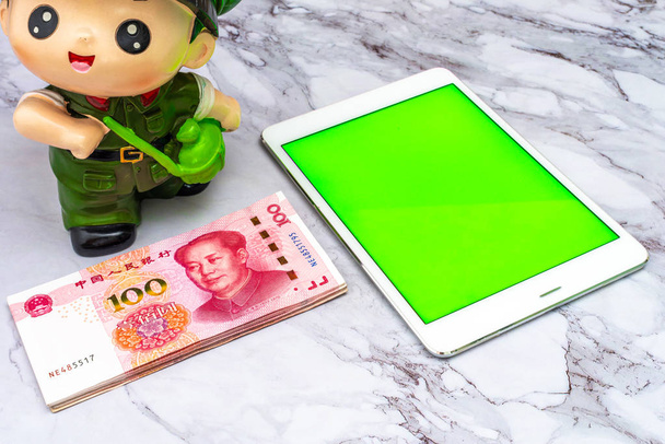 Finance Business concept. China Chinese Yuan RMB bank notes, and green screen touchscreen tablet on table. - Photo, Image