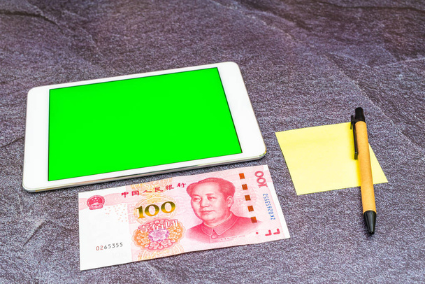 Concetto Finance Business. Una banconota cinese Yuan RMB e un tablet touchscreen verde sul tavolo
. - Foto, immagini