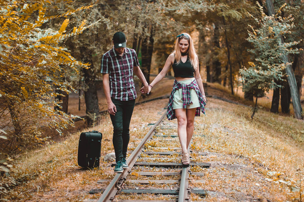 A young couple of lovers missed the train. Walking on the rails in the autumn forest waiting for the next train. - Photo, Image