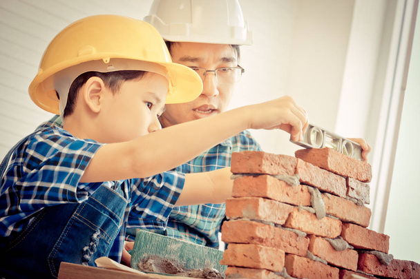 El niño está aprendiendo a poner ladrillos de su construcción.
 - Foto, Imagen
