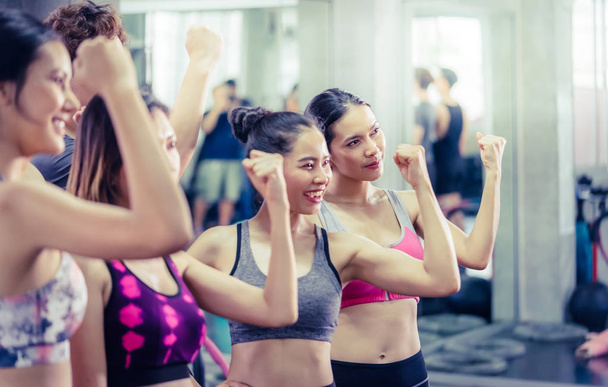 Skupina šťastných lidí je cvičení ve fitness tělocvičně, ukazuje mus - Fotografie, Obrázek