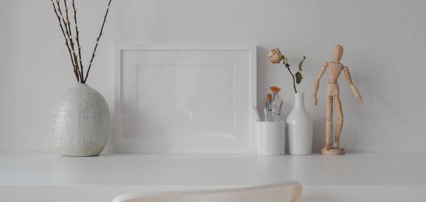 Мінімальна кімната з макетною рамкою з керамічними прикрасами на білому столі з білим фоном стіни
  - Фото, зображення