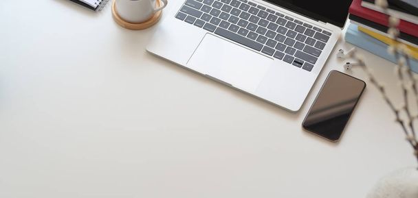 Bovenaanzicht van comfortabele werkruimte met laptop computer en kantoorbenodigdheden op witte houten tafel  - Foto, afbeelding