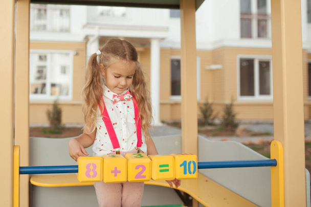 Csinos kislány megtanul számolni, óvodás az óvodában a játszótéren. - Fotó, kép