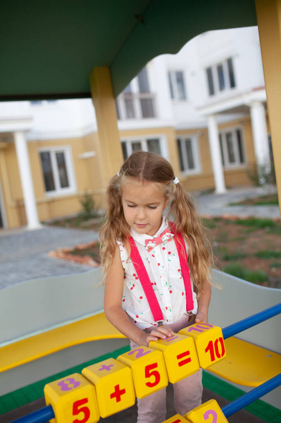 Niña bonita aprender a contar, preescolar en el jardín de infantes en el patio de recreo
 - Foto, imagen