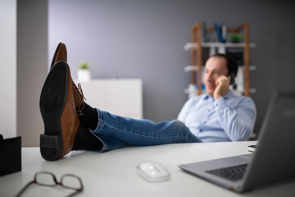Lazy Man Using Phone At Work Desk Instead Of Working - 写真・画像