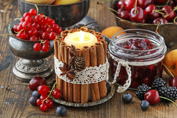 Candle decorated with cinnamon sticks among autumn fruits and fl - Foto, Imagem