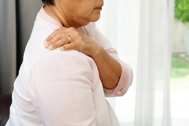 боль в шее и плече, пожилая женщина, страдающая от травмы шеи и плеча, концепция проблем со здоровьем - Фото, изображение